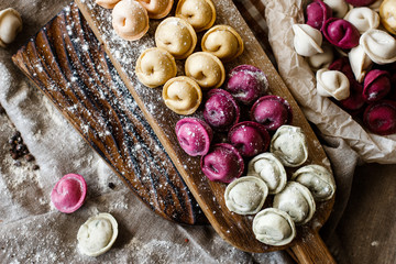Fresh pink yellow beet dumplings or ravioli stuffed with ricotta cheese with butter sauce on wooden...