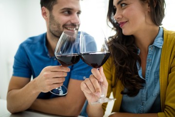 Couple toasting glasses of red wine in the kitchen