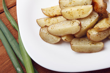 Baked potatoes with green onions on a white plate. Organic Vegetarian Food on wooden background