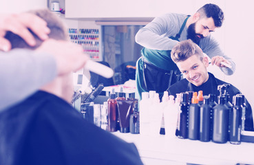 male hairdresser doing haircut for male client at hair salon