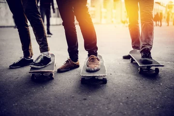 Foto auf Acrylglas Boys skateboarders Feet in pants and bryaks in frayed sneakers stand on the skateboard. Concept of a team of friends doing sports on the asphalt skateboarding © Parilov