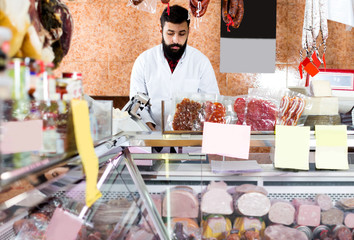 Male shop assistant demonstrating meat