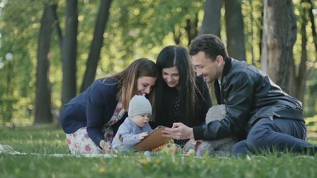 Young swedish family relaxing in green park with little son