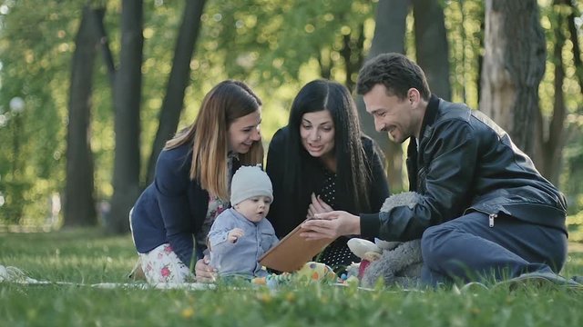 Young swedish family relaxing with little boy on coverlet in park