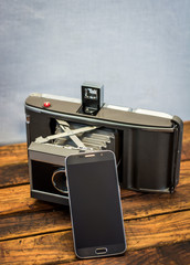 Vintage camera next to a cell phone