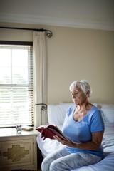 Senior woman reading a book in the bedroom