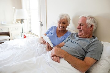 Senior couple using digital tablet in the bedroom