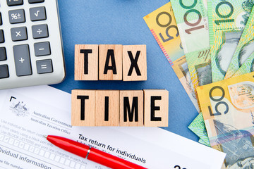 Tax Time - Australia - wooden letters with tax form, money and calculator
