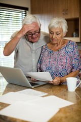 Senior couple calculating their invoices with laptop 