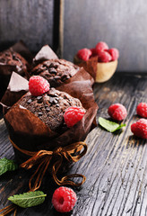 Chocolate muffins with fresh raspberries and mint on a old  black textured wooden table.Free text space.