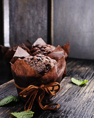 Chocolate muffins with fresh raspberries and mint on a old  black textured wooden table.Free text space.