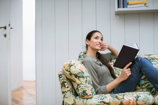 beautiful woman reading boo on colourful sofa