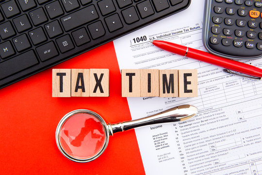 Tax Time - USA - wooden letters with 1040 Tax Form, magnifying glass, keyboard and calculator
