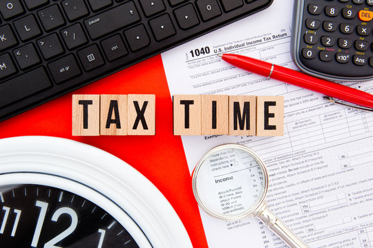 Tax Time - USA - wooden letters with 1040 Tax Form, magnifying glass, clock, keyboard and calculator
