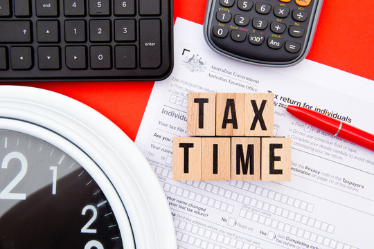 Tax Time - Australia - wooden letters with Tax Form, clock, keyboard and calculator
