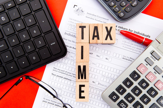Tax Time - Australia - wooden letters with Tax Form, eyeglasses, keyboard and calculator
