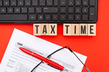Obraz premium Tax Time - USA - wooden letters with 1040 Tax Form, eyeglasses and keyboard 