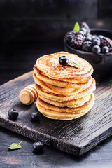 Stack of pancakes with fresh berries served on old black board . Selective focus.