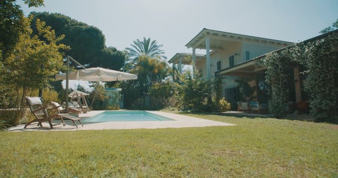 Tracking shot of a large backyard with a swimming pool in a luxury house