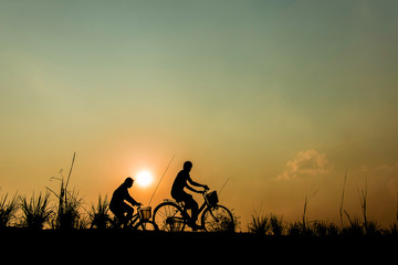 silhouette of couple driving bike happy time sunset