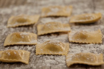 Ravioli pasta dusted with floor on wooden background