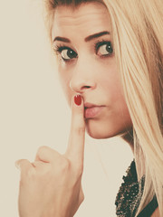 Attractive blonde woman making silence gesture