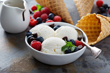 Vanilla ice cream scoops in a bowl with fresh berries