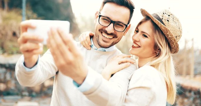 Beautiful couple taking selfies and smiling while traveling