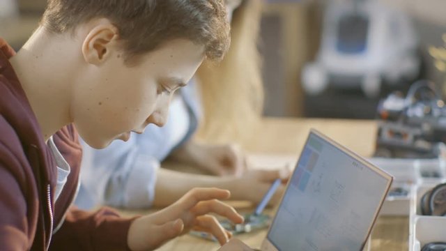 Smart Young Boy Works on a Laptop For His New Project in His Computer Science Class. Shot on RED EPIC-W 8K Helium Cinema Camera.