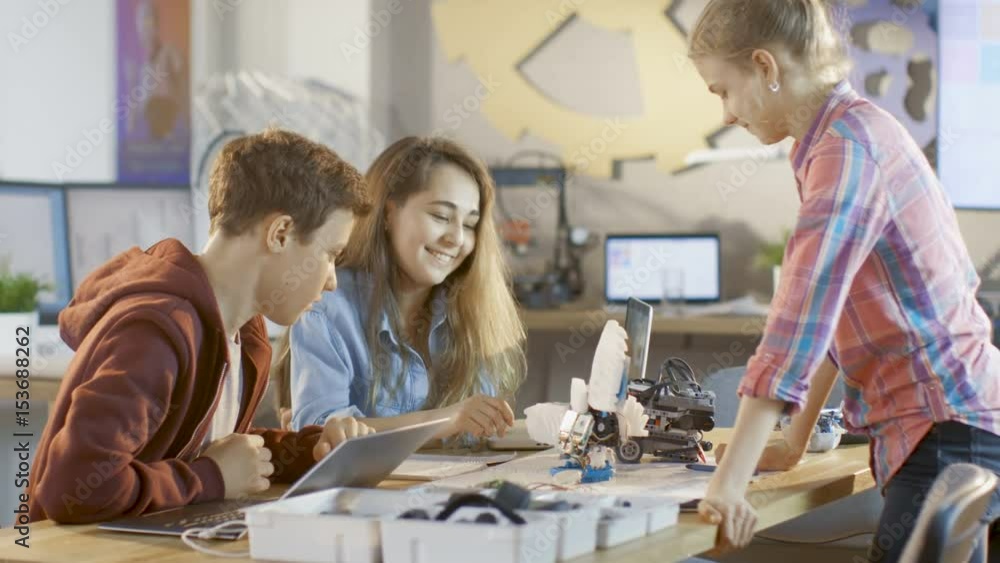 Poster boy and two girls working on a schools science class project. they program and build cute robot. sho