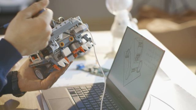 In Computer Science Class Teacher Examines programed Robot Sketched and Engineered by His Student for School Project. Shot on RED EPIC-W 8K Helium Cinema Camera.