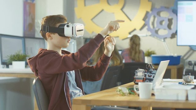 In a Computer Science Class Boy Wearing Virtual Reality Headset Works on Programing Gestures for the Project.Shot on RED EPIC-W 8K Helium Cinema Camera.