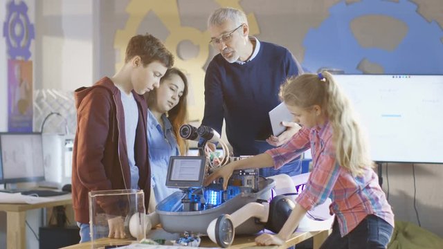 Teacher and His Pupils Work on a Programable Robot with LED Illumination for School Science Class Project.Shot on RED EPIC-W 8K Helium Cinema Camera.