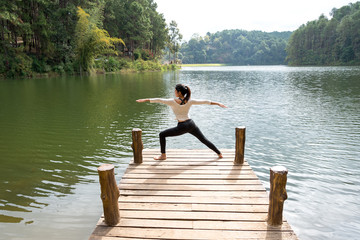 Fototapeta na wymiar Healthy woman practicing yoga on the bridge in the nature