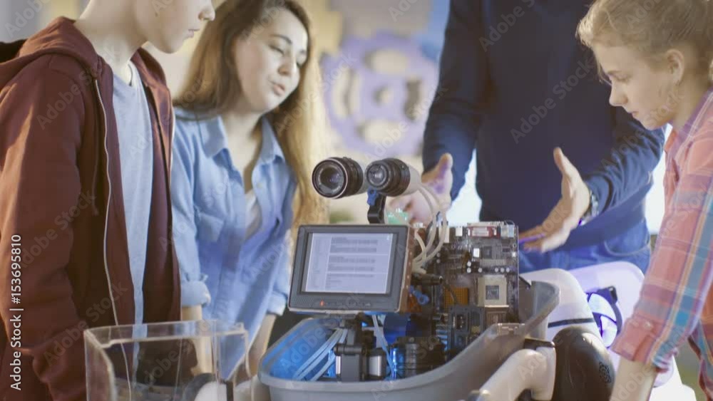 Poster teacher and his pupils work on a programable robot with led illumination for school science class pr