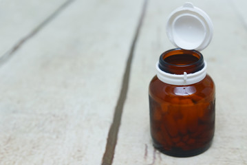 medicine glass bottle packaging and tablets over white wooden backgrounds