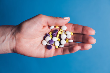 Hand holding pills on blue background