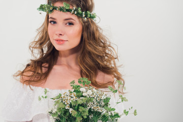 Naklejka premium Beautiful portrait of a girl with flowers head wreath and bouquet in her hands