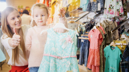 Fototapeta na wymiar Little girl shows the selected blue dress