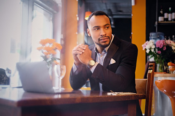 Thoughtful male in a cafe using laptop.