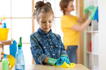 Kid girl and mother make cleaning in room at home