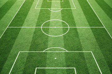 Fußballspielfeld-Bodenlinien auf sonnigem Grasmusterhintergrund. Torseitige Perspektive verwendet.
