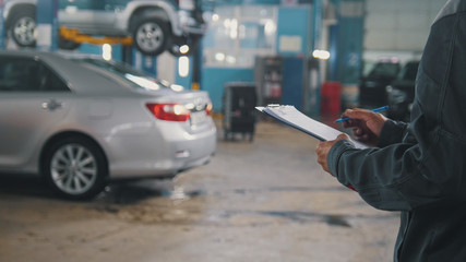 Mechanic doing checking of a car in a garage workshop