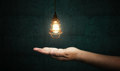 Business man hold bright idea in hand with blue cement background.