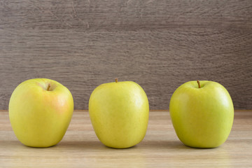 Yellow apples standing in a row on the table.