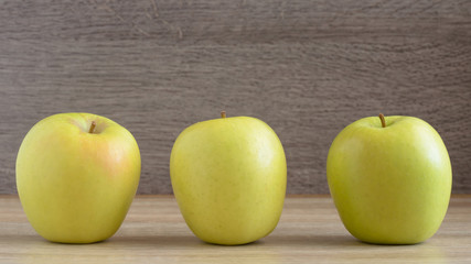 Yellow apples standing in a row on the table.