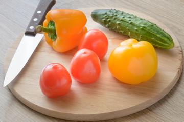Tomatoes and cucumbers and peppers on a cutting board.