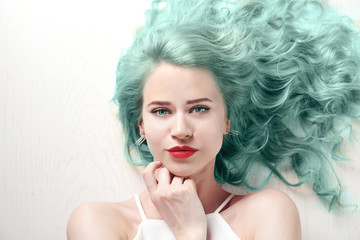 Portrait of young woman with blonde hair on white wooden background
