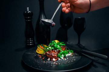 steak in red wine with grilled vegetables and wine on black background