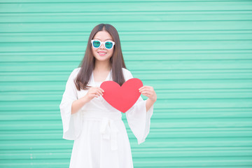 Asian Chinese woman and Valentines day.Young woman holding a red heart shape card with green background.